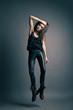 Foto: Fashion model wearing leather pants jump on grey Fashion model wearing leather pants jump on grey