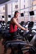 Foto: Attractive man in red sportswear doing exercises on bike at gym Attractive man in red sportswear doing exercises on bike at gym