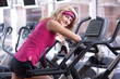 Foto: Tired blonde womandoing exercise on bike in gym Tired blonde womandoing exercise on bike in gym