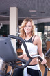 Foto: Beautiful blonde woman doing exercise on bike in gym Beautiful blonde woman doing exercise on bike in gym