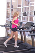 Foto: Attractive woman in pink sportswear running on treadmill at gym Attractive woman in pink sportswear running on treadmill at gym
