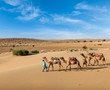 Two cameleers with camels in dunes of Thar deser