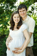Smiling pregnant wife and her husband in park