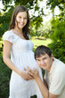 Husband listening to his pregnant wife belly outdoors