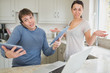 Photo: Busy man using two tablets and laptop with wife holding hands up Busy man using two tablets and laptop with wife holding hands up