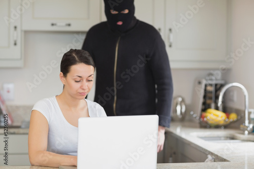 Photo: Woman typing on the laptop while burglar looking at it Woman typing on the laptop while burglar looking at it