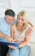 Couple sitting on sofa looking at the tablet