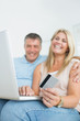 Couple sitting on sofa shopping online