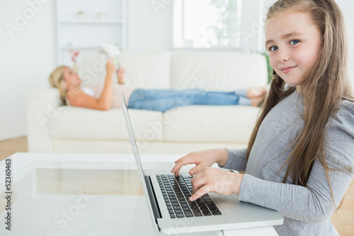 Photo: Girl working on laptop and her mother reading the newspaper Girl working on laptop and her mother reading the newspaper