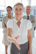 Smiling businesswoman giving a handshake with colleagues behind