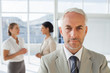 Serious businessman standing while colleague are discussing toge