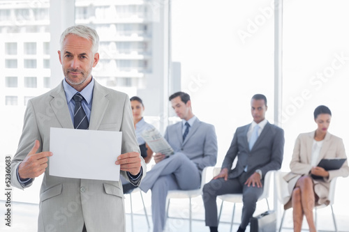 Photo: Serious businessman holding a blank notice Serious businessman holding a blank notice