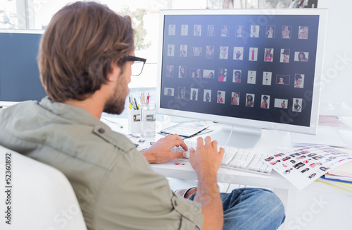 Photo: Photo editor looking at thumbnails on computer Photo editor looking at thumbnails on computer