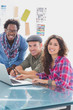 Creative team working together on laptop and smiling at camera