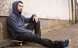 Foto: Skater sitting on his board looking thoughtful Skater sitting on his board looking thoughtful