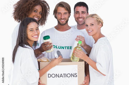 Photo: Happy volunteers putting food in donation box Happy volunteers putting food in donation box