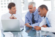Three businessmen watching a laptop