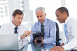 Three business men watching a camera