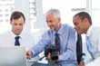 Businessman holding a camera and pointing at the laptop