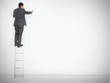 Businessman standing on ladder drawing on large copy space