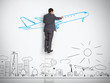 Businessman standing on ladder drawing airplane above town