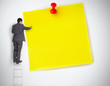 Businessman standing on ladder writing on large yellow note