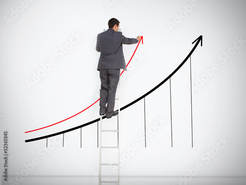 Photo: Businessman standing on ladder drawing graph Businessman standing on ladder drawing graph