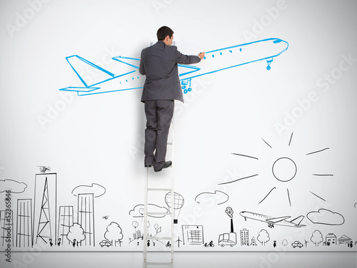 Photo: Businessman standing on ladder drawing airplane above town Businessman standing on ladder drawing airplane above town