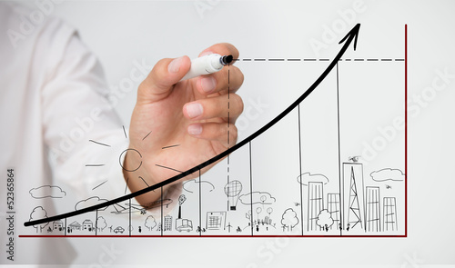 Photo: Businessman drawing graph over town doodle Businessman drawing graph over town doodle