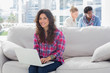 Smiling worker using laptop while sitting on a couch