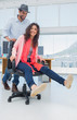 Creative business colleagues having fun on a swivel chair