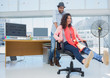 Photo editors having fun on an office chair