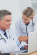 Smiling doctor pointing at a laptop
