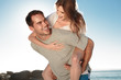 Smiling man giving a piggy back to his girlfriend 