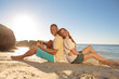 Couple sat back to back on the beach