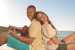 Cheerful couple sat back to back on the beach