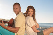 Pretty couple sat back to back on the beach