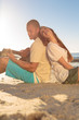 Cute couple sat back to back on the beach