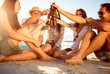 Friends clicking their bottles of beer on the beach