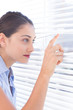 Brunette businesswoman peeking through a roller-blind