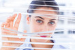 Delighted businesswoman peeking through a venetian blind