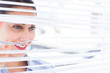 Beautiful businesswoman peeking through venetian blind