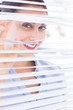 Attractive businesswoman looking through a venetian blind
