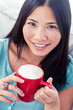 Smiling asian woman holding a cup of coffee