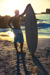 Attractive surfer standing next to his surfboard