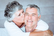 Woman kissing the cheek of her husband in the bed