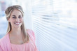 Pretty woman standing next to venetian blinds