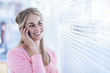 Pretty woman phoning in front of venetian blinds
