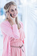 Blonde woman phoning in front of venetian blinds