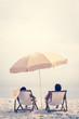 People relaxing on the beach reclining on deck chairs